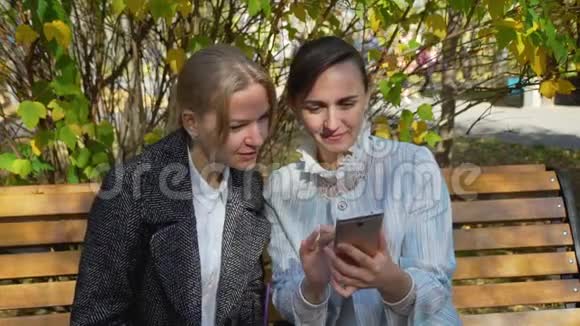 两个美女在智能手机上看照片视频的预览图