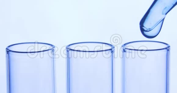 吸管将透明的蓝色化学物质滴入三个试管中化学和医学概念视频的预览图