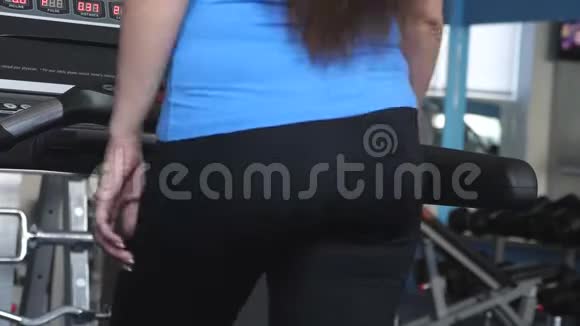 性感的女孩在健身俱乐部的跑步机上散步特写镜头跑步机上的女孩有氧运动负荷加强视频的预览图