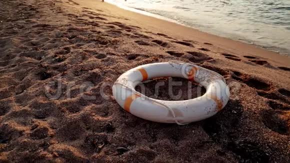 日落时分救生圈环躺在沙滩上的4k镜头视频的预览图