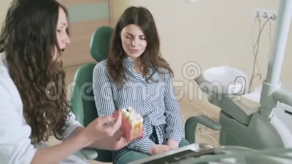 慢慢拍摄的stedikam牙医医生清楚地解释了病人龋齿的原因出示了一个假模假模女孩视频的预览图