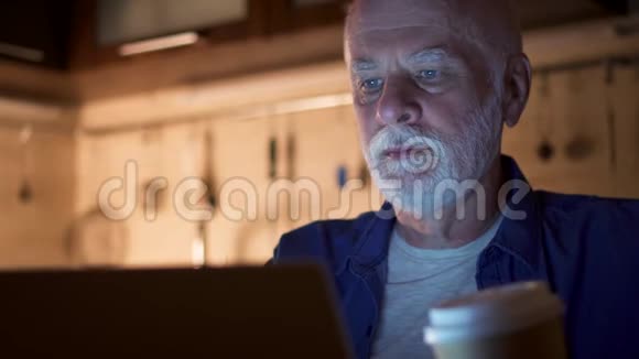 疲倦困倦的高级商人在家庭办公室使用笔记本电脑疲倦的人从纸杯里喝咖啡视频的预览图
