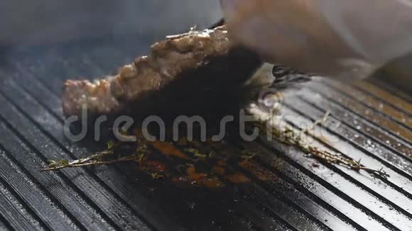 一个厨师慢慢地在烤架上翻出一块肉排视频的预览图