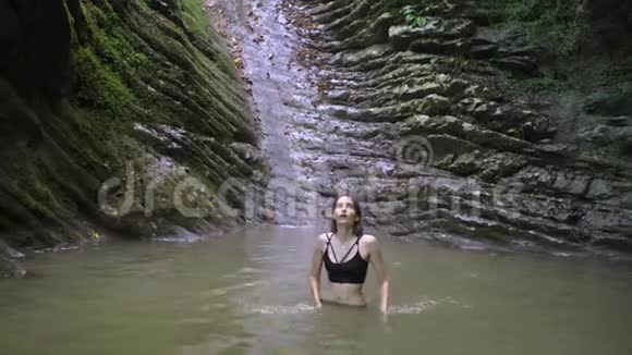 在绿色热带森林的小山湖里洗澡的年轻美女视频的预览图