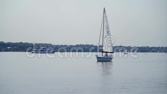 大湖中央的一艘小帆船水上行走视频的预览图