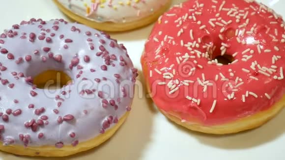 三个甜甜圈白色盘子上撒着五颜六色的花洒不健康的糖滥用成瘾概念视频的预览图