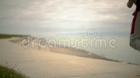 一个年轻的运动员在城市和湖泊的背景下奔跑镜头前侧视慢动作视频的预览图