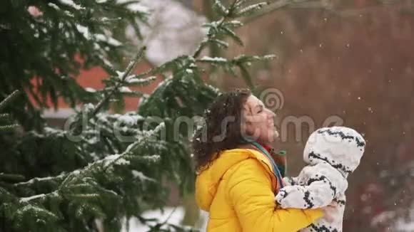 宝宝在妈妈怀里散步冬天走在雪地下的公园里妈妈把宝宝抱起来宝宝看起来视频的预览图
