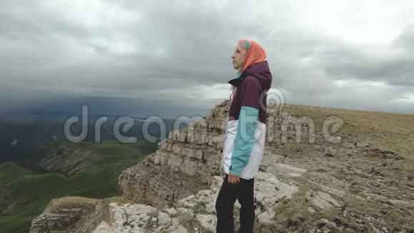 这个女孩在一个高耸的悬崖旁的高原上行走旅游理念视频的预览图