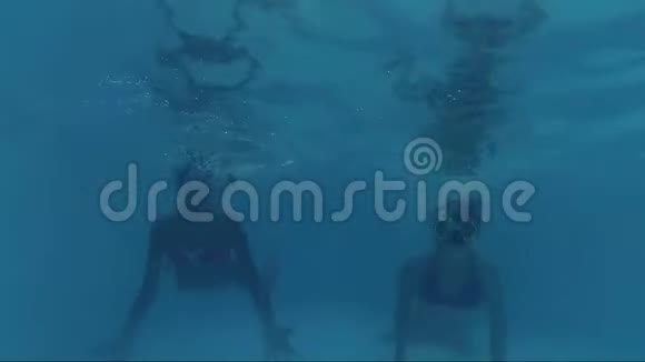 快乐的两个女孩在游泳池里潜水看镜头水下拍摄视频的预览图