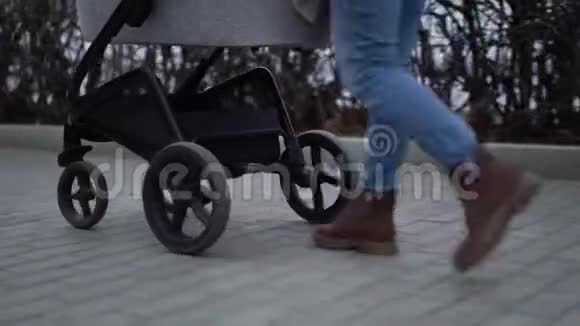 年轻的母亲和一个孩子在婴儿车里散步秋季视频的预览图