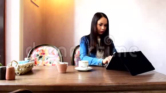 一个女孩坐在一家的咖啡馆里用平板电脑工作视频的预览图