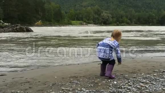 金发小女孩在河里扔石头视频的预览图