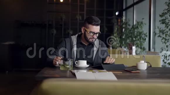 年轻人用平板电脑在咖啡馆喝茶视频的预览图