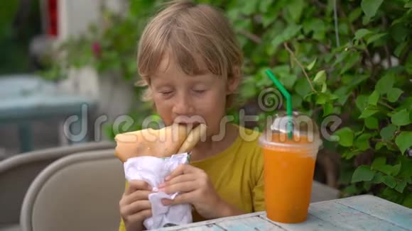 一个小男孩在街头市场吃美味的煎饼的特写镜头街头食品概念视频的预览图