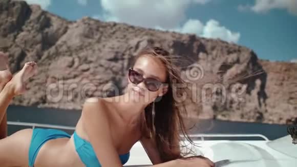 一个穿比基尼慢动作在游艇上日光浴的快乐美丽女孩的肖像视频的预览图