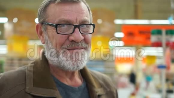 成熟的养老人在超市亲密的肖像悲伤的微笑这个人有着整齐的灰色胡须蓝色的眼睛和光学视频的预览图