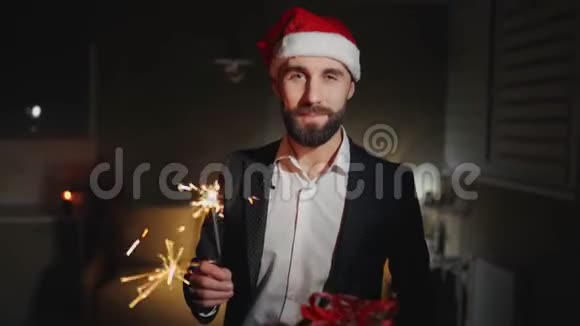 长胡子的商人戴着闪闪发光的帽子圣诞老人戴着圣诞老人的帽子说着祝新年快乐看着摄像机视频的预览图