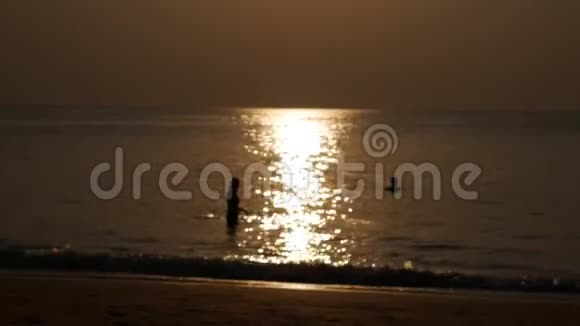 模糊的轮廓人们在海滩上散步在日落时在海里游泳假期概念特写镜头4k视频的预览图