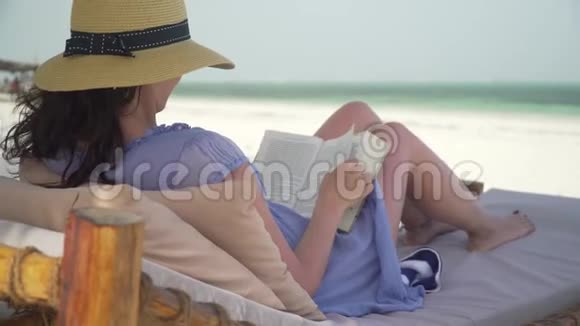 年轻女子在海边的白色海滩上看书视频的预览图