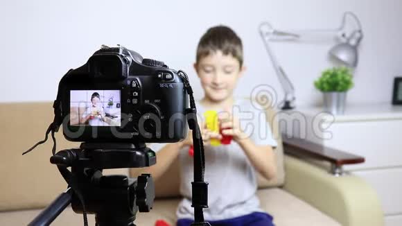 在三脚架上关闭摄像机的视频一个男孩在液晶屏幕上模糊的场景在背景上男童视频博客视频的预览图