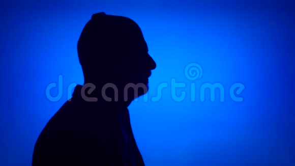 高级男士剪影在蓝色背景上取下耳机男性侧脸听音乐视频的预览图