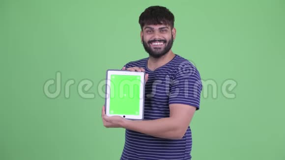 一位年轻体重超重留着胡子的印度小伙子带着数码平板电脑视频的预览图