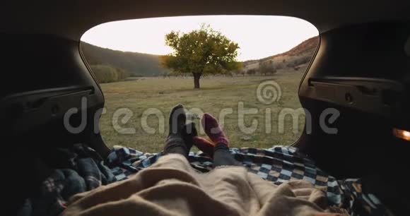 特写视频夫妇与舒适的袜子在汽车后备箱等待日落在自然4k视频的预览图