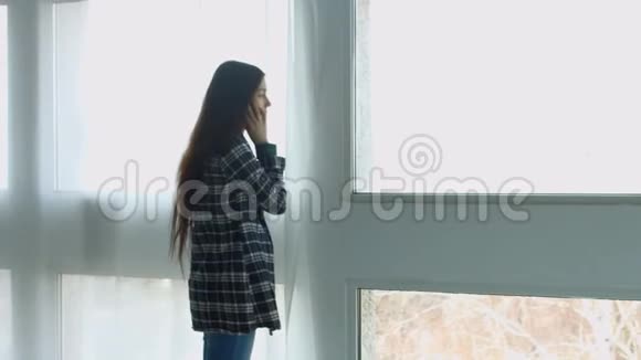 在窗户附近用手机说话的美女视频的预览图