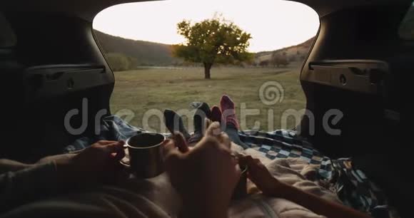 在一辆汽车后备箱里夫妻俩在一起玩得很开心穿着舒适的袜子和毯子手牵着手喝着前茶视频的预览图
