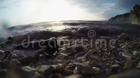 在岩石上的岩石海岸在日落时海浪在岩石上翻滚阳光灿烂视频的预览图