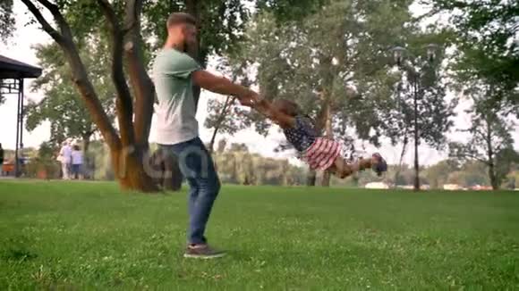 英俊的父亲正在摇着他的小女儿她奔跑着黎明家庭观念视频的预览图