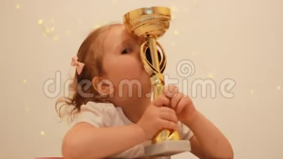 小女孩为胜利和奖赏而欢欣鼓舞亲吻并拥抱冠军冠军杯获得冠军第一名视频的预览图