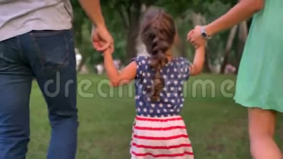 年轻的一家人夏天在公园里散步抱着女儿玩着概念视频的预览图