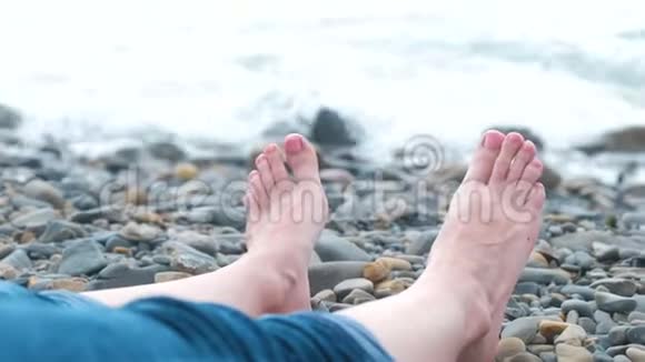 女人脚穿牛仔裤靠在沙滩上的海边视频的预览图