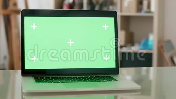 玻璃办公桌上有绿色屏幕的笔记本电脑视频的预览图