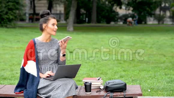 快乐微笑的女人在公园的户外用手机说话视频的预览图
