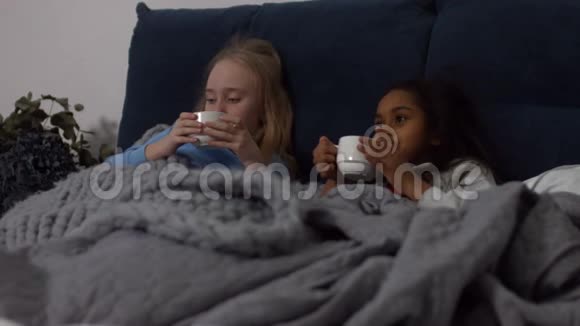患病的多民族儿童在床上喝热茶视频的预览图