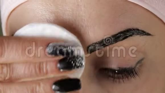 染眉毛女性特写用棉垫去除多余的油漆视频的预览图