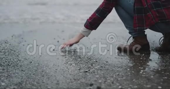 雨天站在海边的人手上拿着一些湿沙把湿沙从手里扔下来视频的预览图