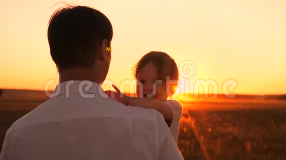 爸爸在日落时抱着小女儿波普和太阳的孩子们在公园里散步视频的预览图