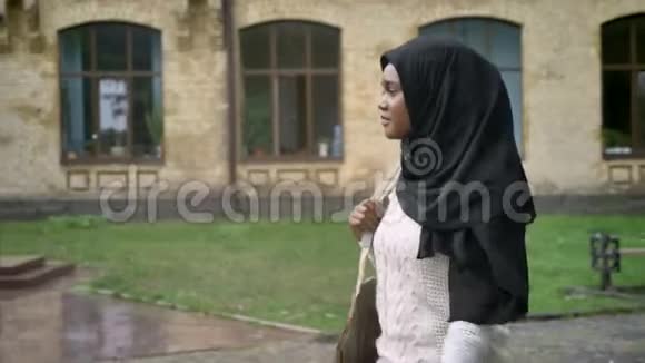 美丽的非洲裔美国穆斯林妇女戴着头巾在大学附近的公园散步迷人的女学生人行道视频的预览图