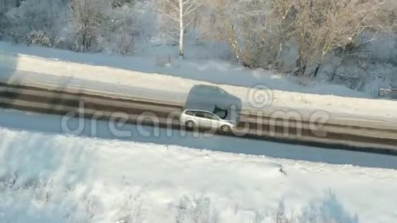 在白雪皑皑的森林里骑着车鸟瞰雪林松树高路上有车视频的预览图