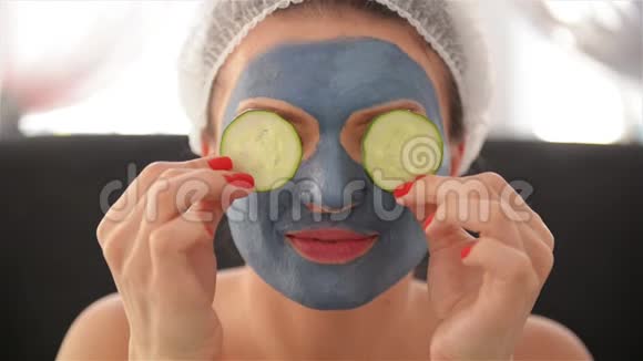 一个女孩脸上戴着面具头上戴着毛巾用黄瓜和微笑闭上眼睛妇女视频的预览图