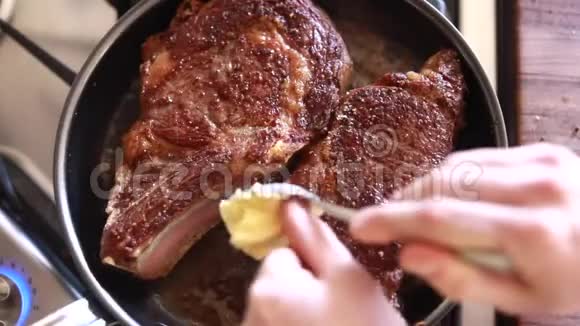 厨师用黄油大蒜和迷迭香在不粘锅中煎肋眼牛排视频的预览图