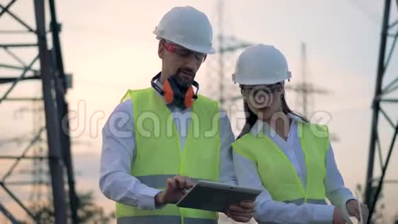 能源变电站巡视期间男女工程师安全帽讨论建设项目视频的预览图