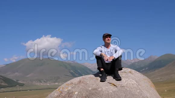 人坐在岩石上在旅途中欣赏美丽的山景视频的预览图
