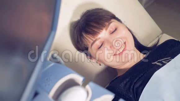 靠近一位女士的笑脸她躺在医疗设备旁边的沙发上视频的预览图
