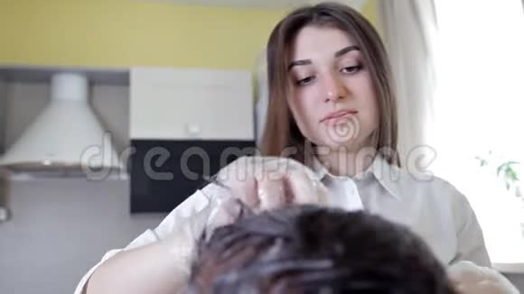 年轻的发型师发型师把头发的颜色涂在女人身上深色头发着色工艺视频的预览图