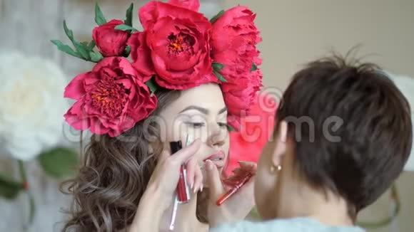 化妆师和模特一起工作造型师用红色铅笔画出模型嘴唇的轮廓视频的预览图